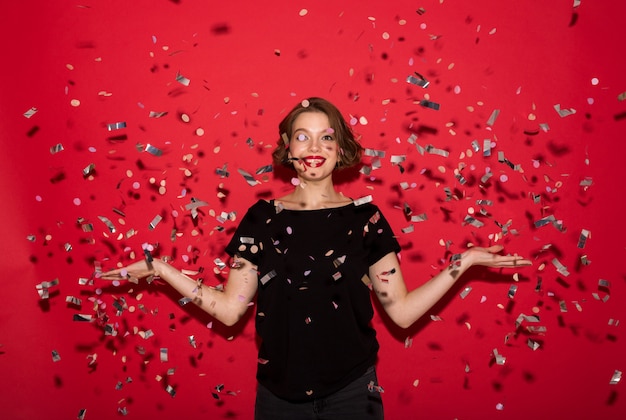 Young beautiful cheerful lady catching sequins while looking