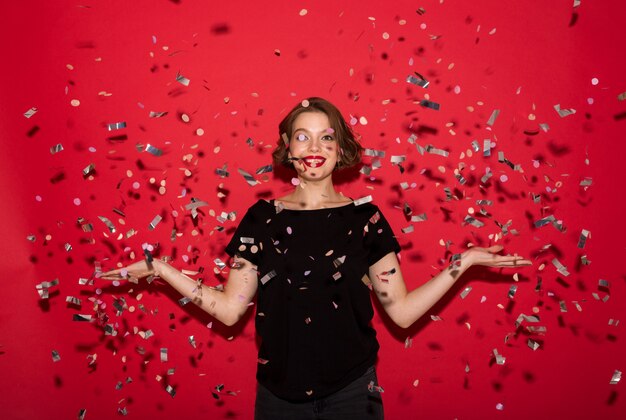 Young beautiful cheerful lady catching sequins while looking