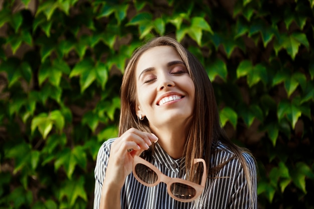 Young beautiful cheerful woman in sunglasses walking around city, smiling.