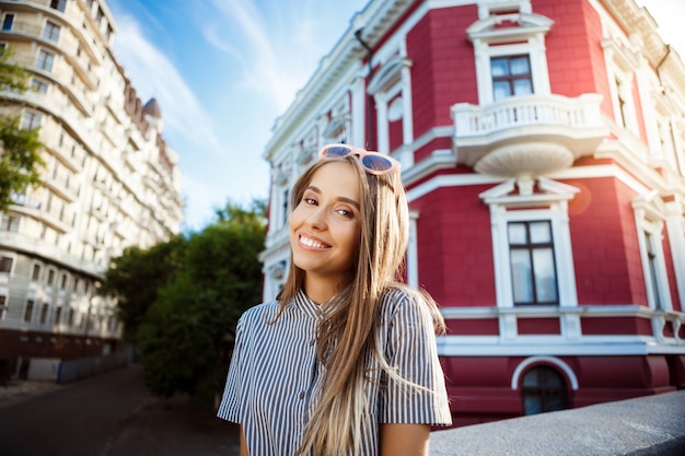 Foto gratuita giovane bella donna allegra in occhiali da sole a spasso per la città, sorridente.