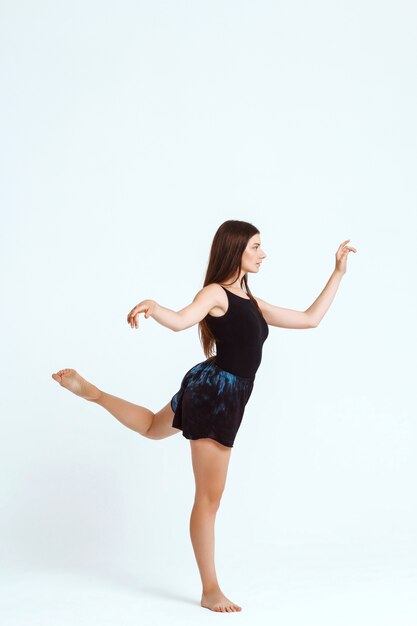 Young beautiful contemporary dancer posing over white wall. Copy space.