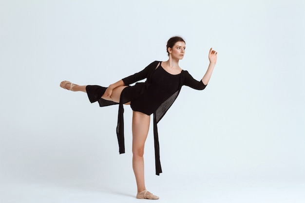 Young beautiful contemporary dancer posing over white wall. Copy space.