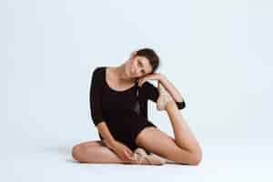 Free photo young beautiful contemporary dancer posing over white wall. copy space.