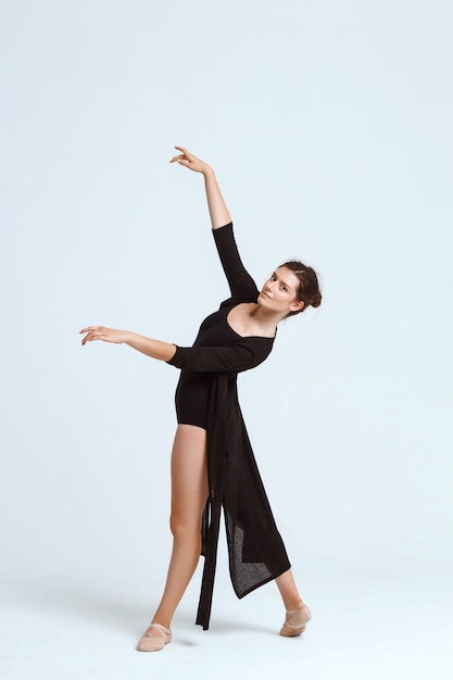 Young beautiful contemporary dancer posing over white wall. Copy space.