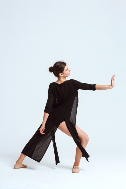 Young beautiful contemporary dancer posing over white wall. Copy space.