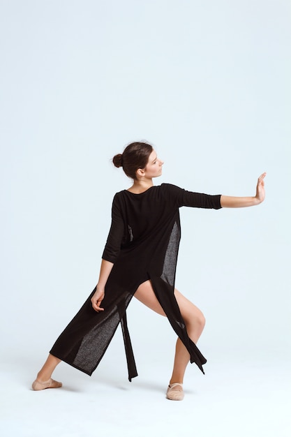 Young beautiful contemporary dancer posing over white wall. Copy space.