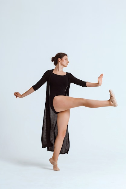 Young beautiful contemporary dancer posing over white wall. Copy space.