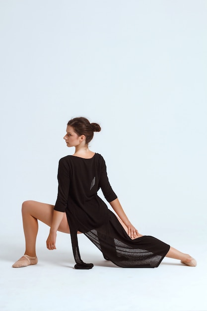 Young beautiful contemporary dancer posing over white wall. Copy space.