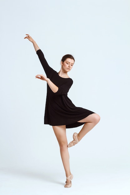 Young beautiful contemporary dancer posing over white wall. Copy space.