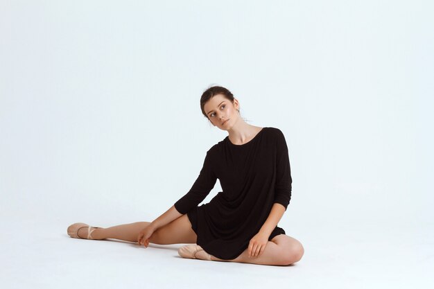 Young beautiful contemporary dancer posing over white wall. Copy space.