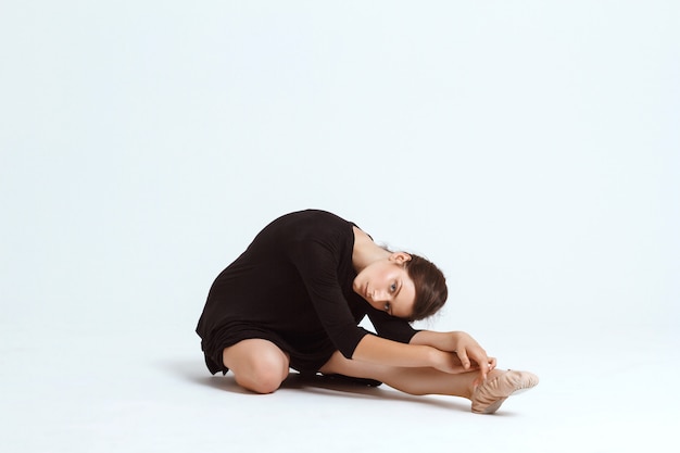 Young beautiful contemporary dancer posing over white wall. Copy space.