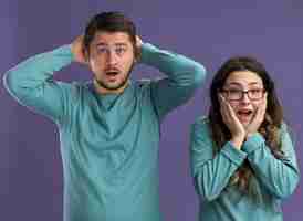 Foto gratuita giovane bella coppia in abiti casual blu stupito e sorpreso uomo e donna in piedi sul muro viola