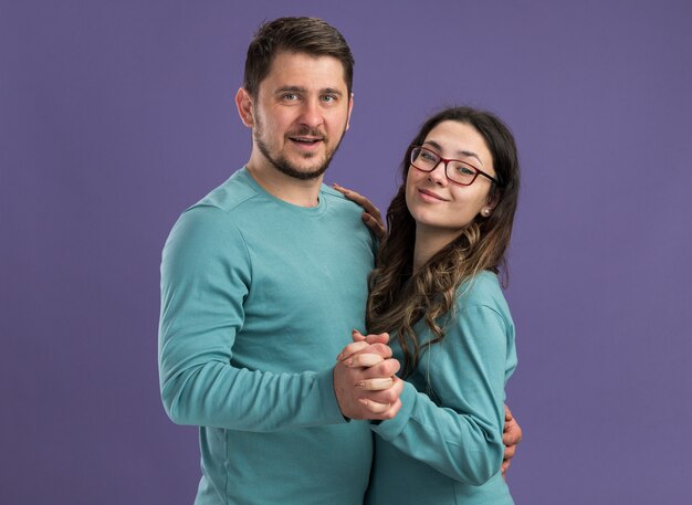 Young beautiful couple in blue casual clothes happy and cheerful smiling man and woman dancing together happy in love standing over purple wall