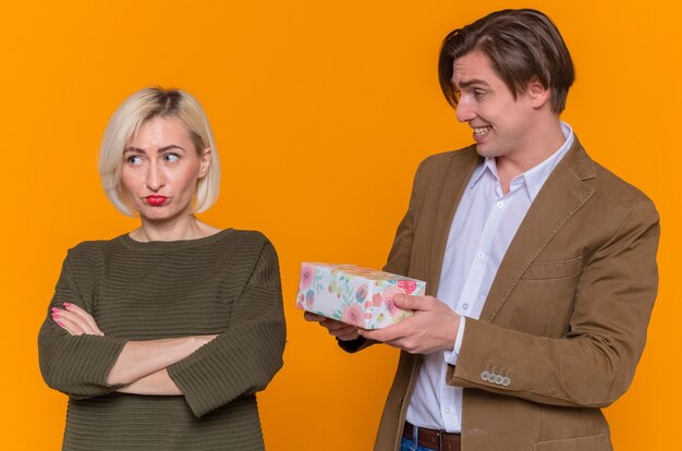 Young beautiful couple happy man giving a present to his displeased offended girlfriend