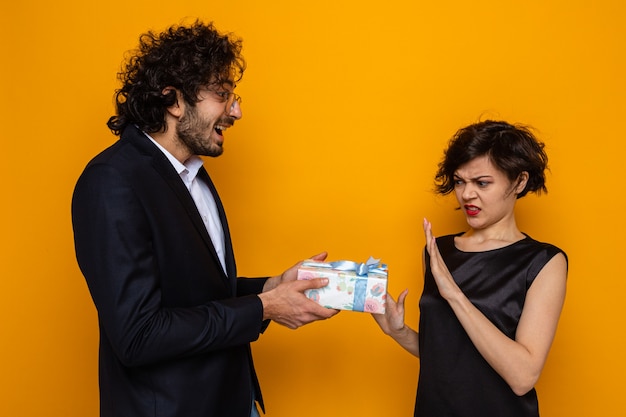 Young beautiful couple happy man giving a present to his refusing displeased girlfriend celebrating valentine