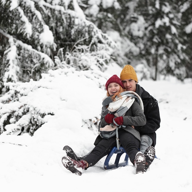 Young beautiful couple having fun sitting on the sleigh