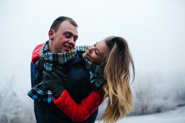 雪に覆われた公園で楽しんでいる若い美しいカップル