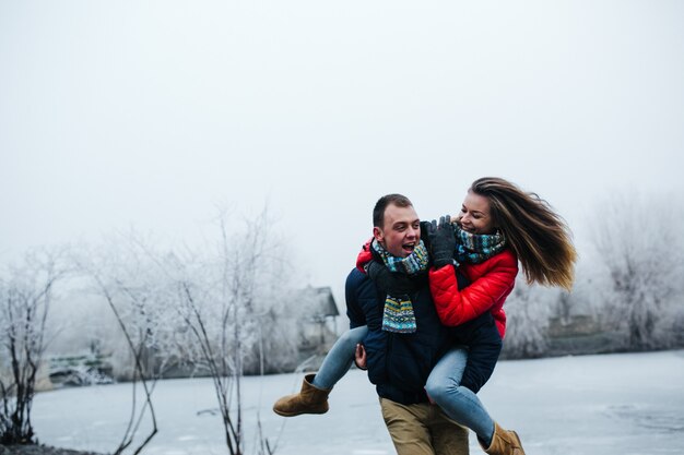 Young beautiful couple having fun in the snow-covered park