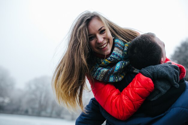 Young beautiful couple having fun in the snow-covered park