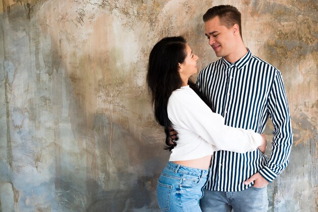 Young beautiful couple hugging against concrete wall