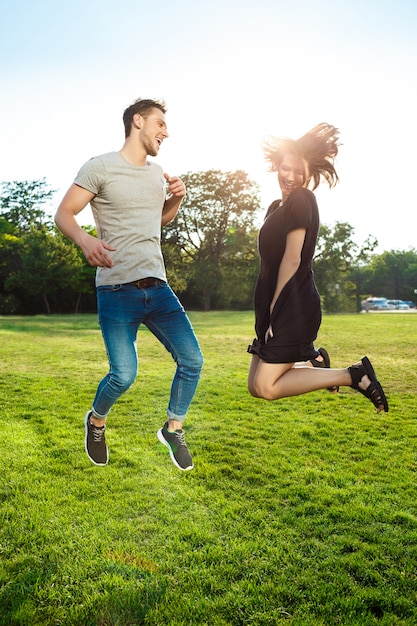 Young beautiful couple jumping at the park.