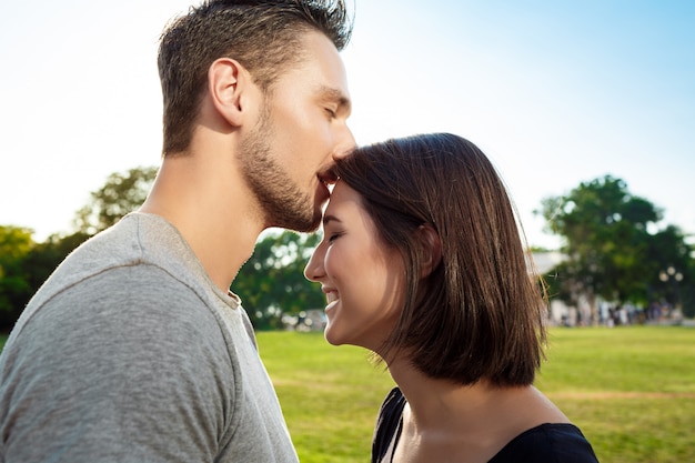 若い美しいカップルが公園でキスします。