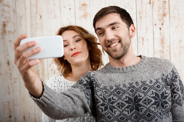 Young beautiful couple making selfie smiling over wooden wall