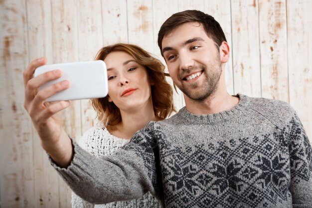 나무 벽에 웃 고 selfie을 만드는 젊은 아름 다운 부부