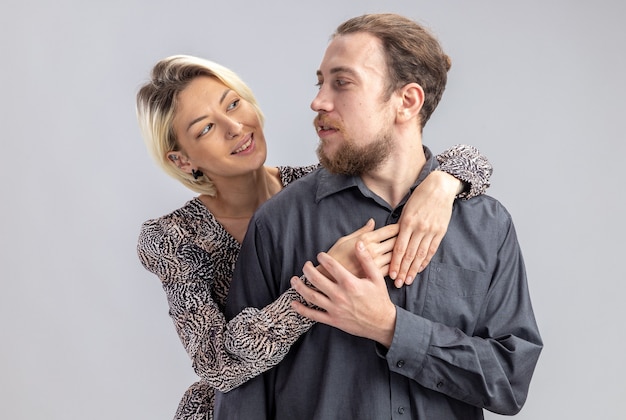 young beautiful couple man and woman happy in love embracing celebrating valentines day standing over white wall