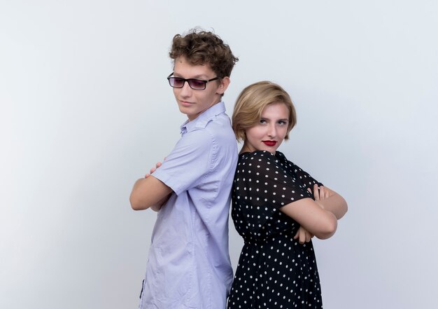 Free photo young beautiful couple man and woman looking confident standing back to back over white wall