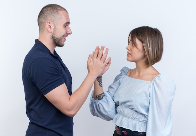 Free photo young beautiful couple man and woman looking at each other touching by hands happy and confident standing