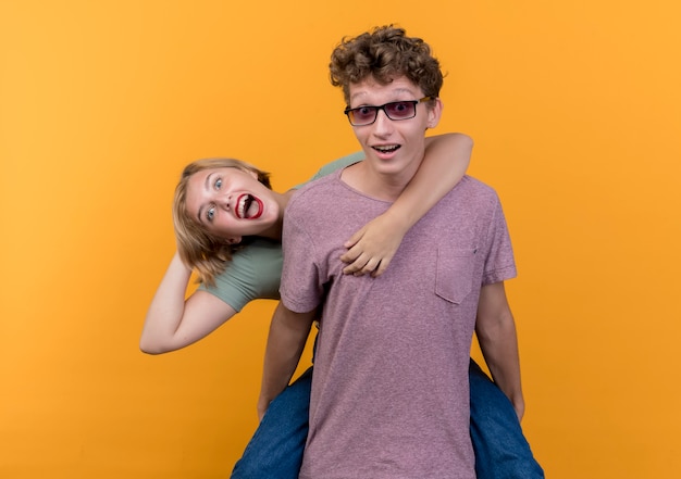 Free photo young beautiful couple man and woman wearing casual clothes having fun together happy and positive standing over orange wall