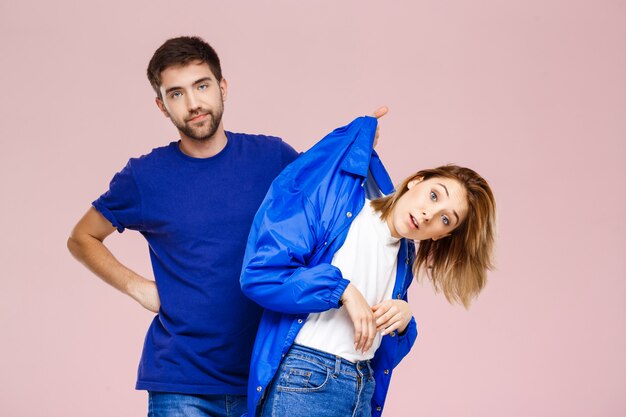 Young beautiful couple posing having fun  over light pink wall