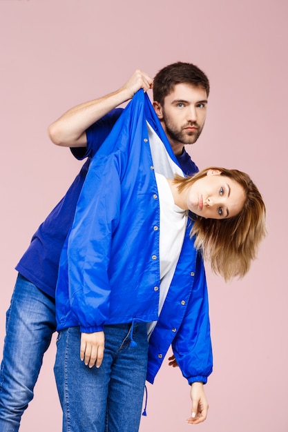 Free photo young beautiful couple posing having fun  over light pink wall