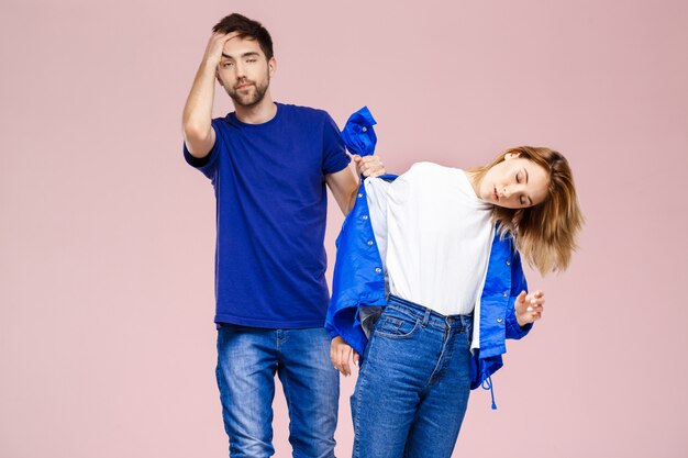 Young beautiful couple posing having fun  over light pink wall