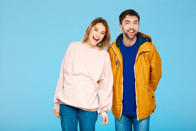 Free photo young beautiful couple posing smiling having fun over blue wall