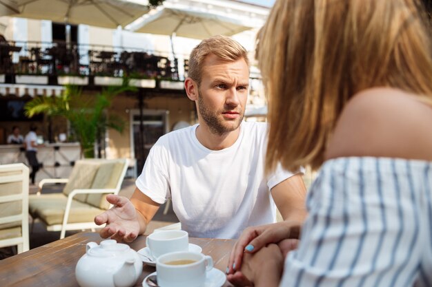 Young beautiful couple quarreling, sitting in cafe.