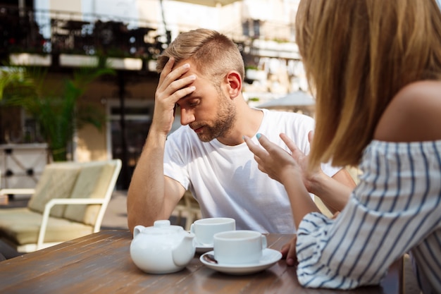 Young beautiful couple quarreling, sitting in cafe.