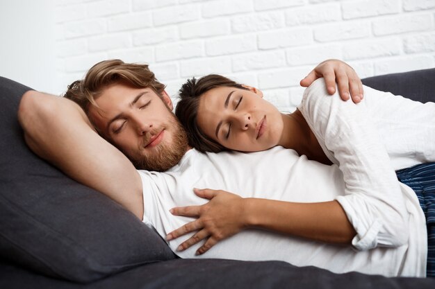 Young beautiful couple relaxing resting lying on sofa at home.