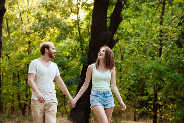 休んで、公園を歩いて、笑って、喜んで若い美しいカップル。