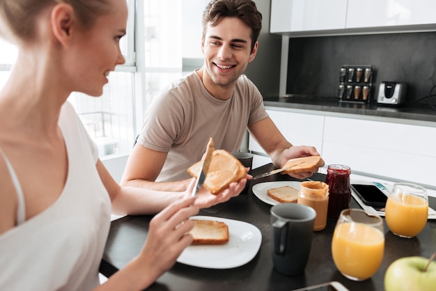 Young beautiful couple sitting in kitchen and have breakfast