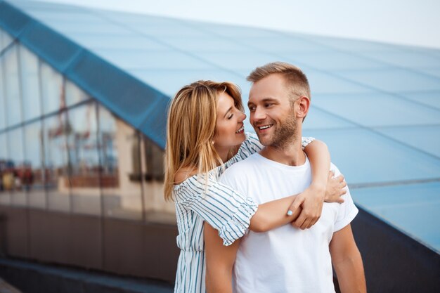 Young beautiful couple smiling, embracing, walking around city.