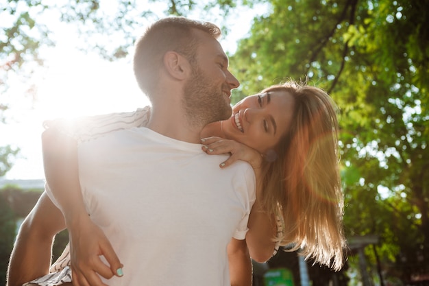 Young beautiful couple smiling, embracing, walking in park.