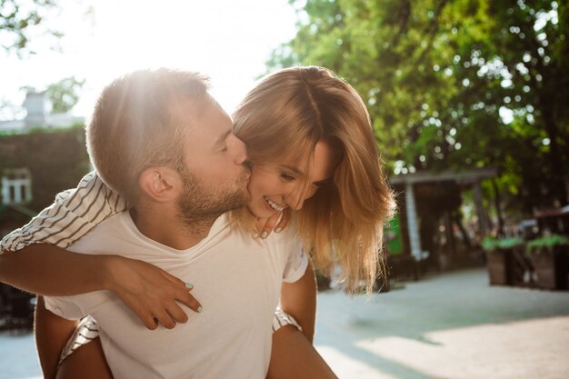 笑顔、キス、抱きしめる、公園を歩いている若い美しいカップル。