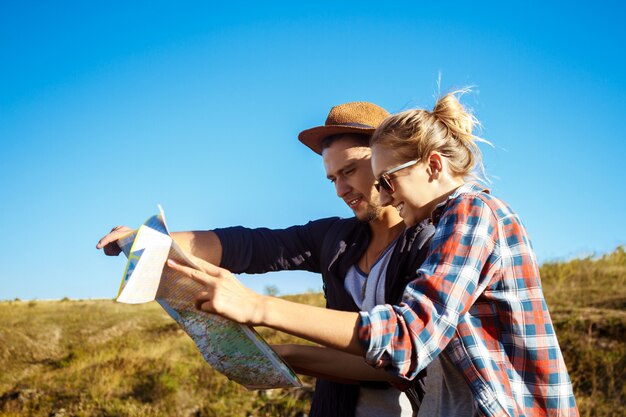 Young beautiful couple smiling, looking for route on map