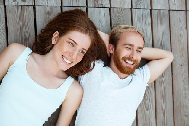 Young beautiful couple smiling, lying on wooden boards
