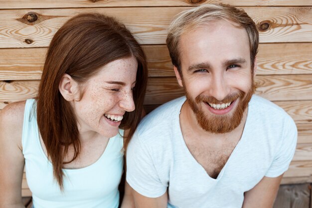 若い美しいカップル笑顔、木の板の背景にポーズ