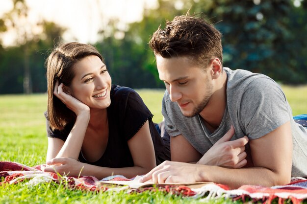 Young beautiful couple smiling, reading, resting at park