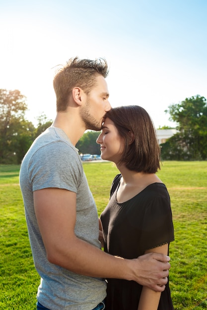 Young beautiful couple smiling, relaxing, kissing in park