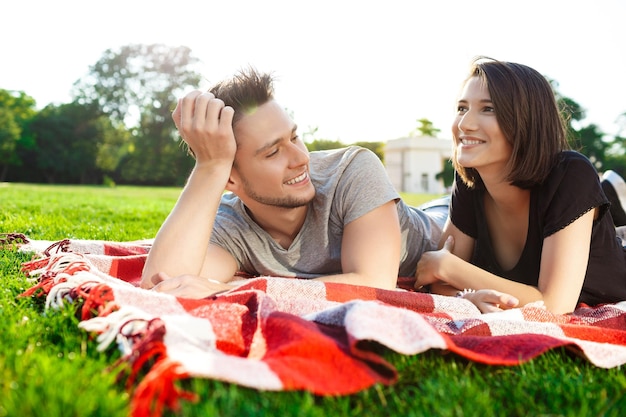 Free photo young beautiful couple smiling resting on picnic in park